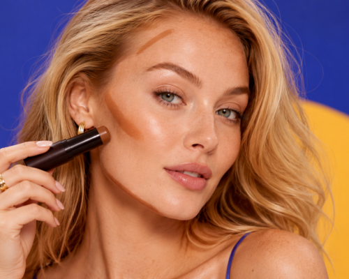 Kobieta nakłada bronzer w sztyfcie pod kość policzkową, na czoło i linię żuchwy.